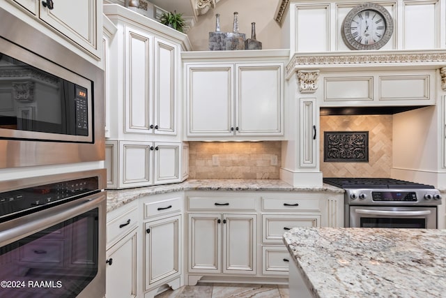 kitchen featuring stainless steel appliances, decorative backsplash, and light stone countertops