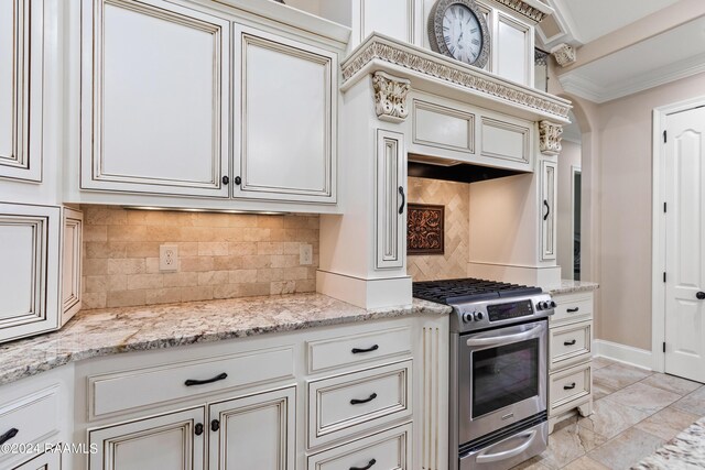 kitchen with tasteful backsplash, stainless steel range with gas cooktop, light stone countertops, and light tile patterned floors