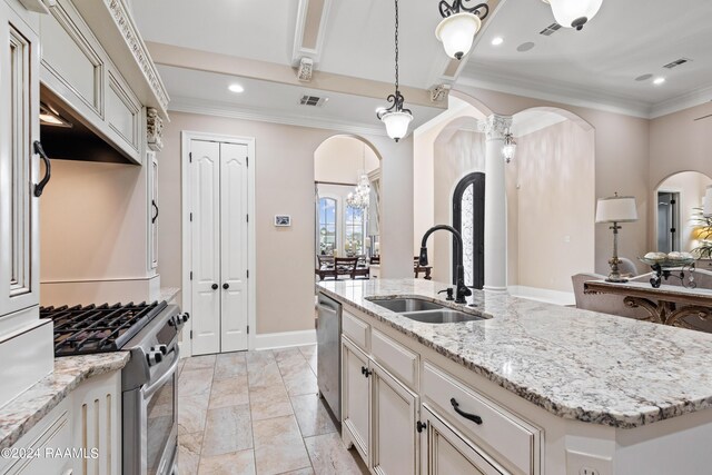 kitchen with sink, appliances with stainless steel finishes, light stone countertops, a kitchen island with sink, and light tile patterned floors