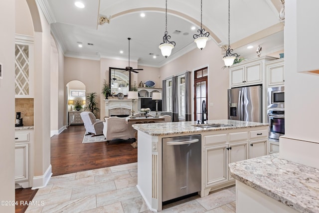 kitchen featuring an island with sink, appliances with stainless steel finishes, open floor plan, hanging light fixtures, and a sink