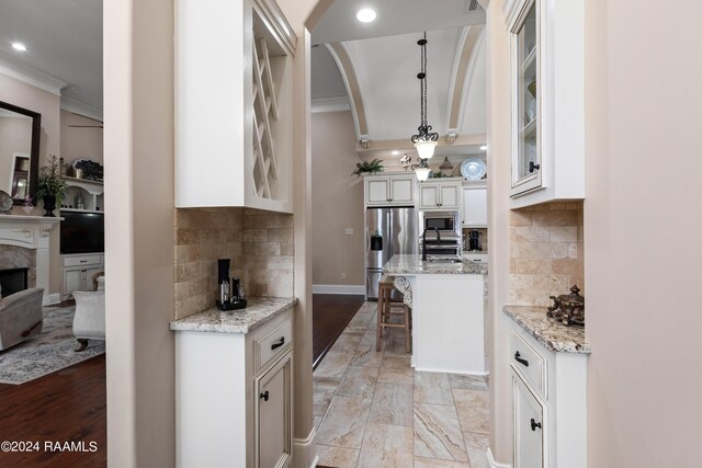 kitchen with a kitchen breakfast bar, light wood-type flooring, decorative backsplash, stainless steel appliances, and pendant lighting