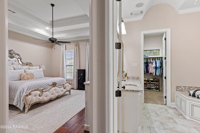 tiled bedroom featuring ceiling fan, a raised ceiling, ornamental molding, a closet, and sink