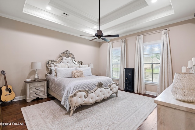 bedroom with a tray ceiling, ceiling fan, crown molding, and dark hardwood / wood-style floors