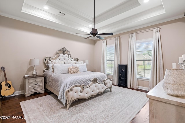 bedroom featuring a tray ceiling, dark wood finished floors, visible vents, and baseboards