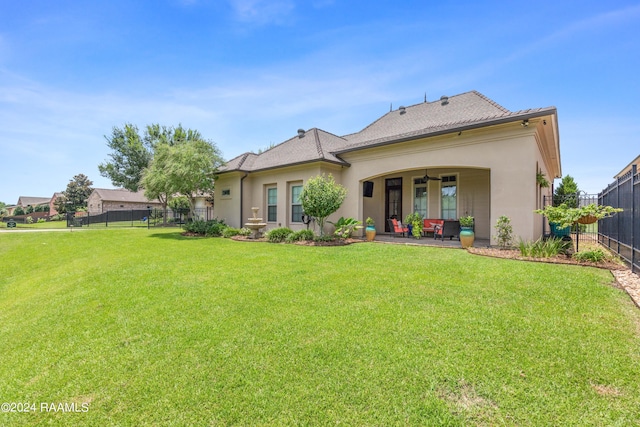 rear view of house featuring stucco siding, a fenced backyard, a yard, and a patio