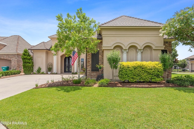 view of front of property featuring concrete driveway, a front yard, and stucco siding