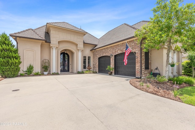 view of front of property featuring driveway, stucco siding, a garage, and brick siding