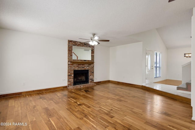 unfurnished living room featuring a fireplace, hardwood / wood-style floors, a textured ceiling, ceiling fan, and lofted ceiling