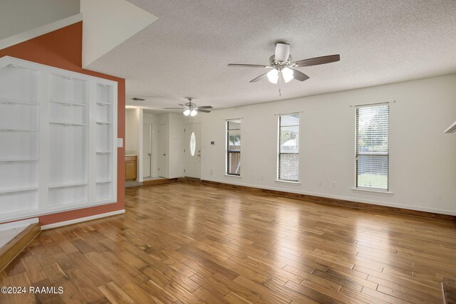 unfurnished living room with ceiling fan, hardwood / wood-style flooring, and a textured ceiling