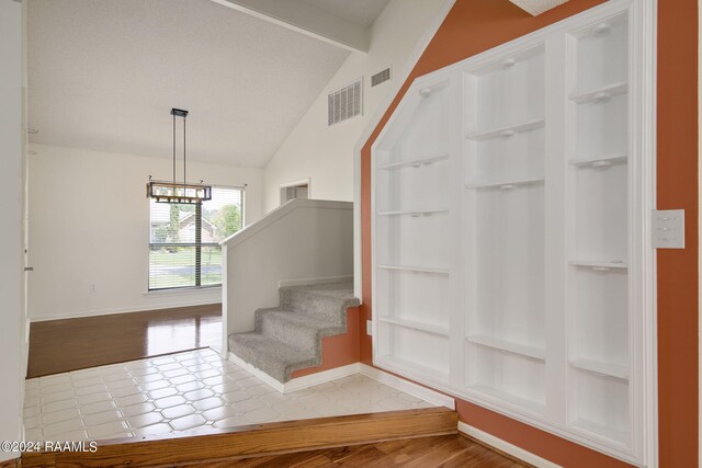 staircase featuring wood-type flooring, a chandelier, and lofted ceiling with beams