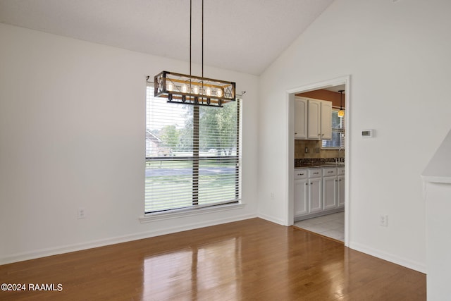 unfurnished dining area featuring lofted ceiling, light hardwood / wood-style flooring, and sink