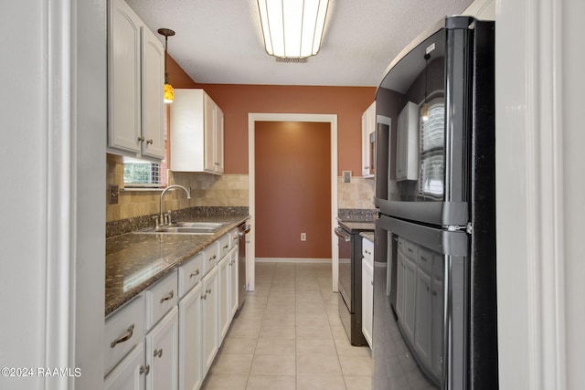 kitchen featuring black refrigerator, white cabinetry, and sink