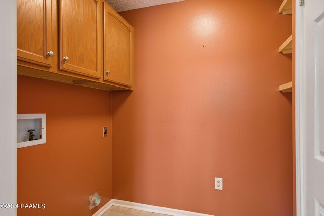 laundry area featuring cabinets, hookup for a washing machine, a textured ceiling, light tile patterned floors, and hookup for an electric dryer