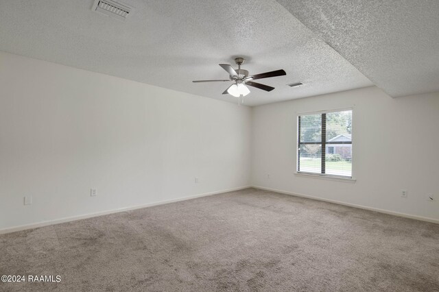 empty room with a textured ceiling, carpet, and ceiling fan