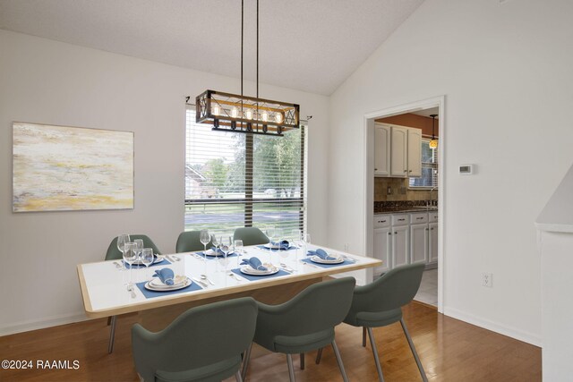 dining space featuring lofted ceiling, dark hardwood / wood-style flooring, and sink