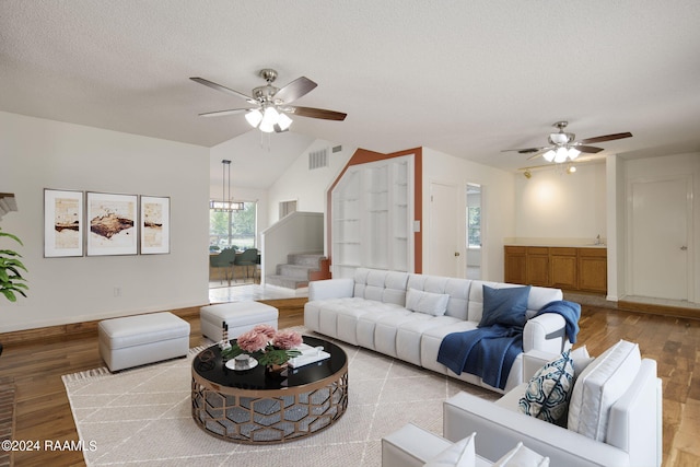 living room featuring vaulted ceiling, a textured ceiling, light hardwood / wood-style flooring, and ceiling fan