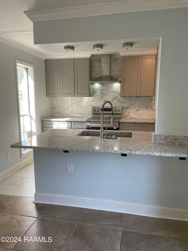 kitchen featuring sink, dark tile patterned flooring, light stone counters, tasteful backsplash, and wall chimney range hood