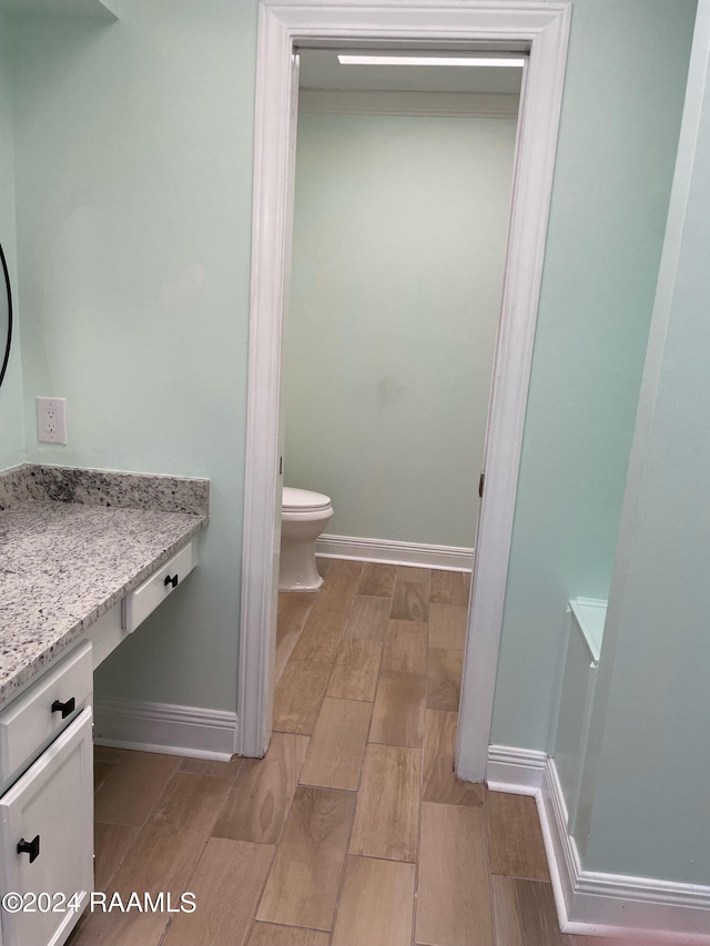 bathroom featuring toilet, hardwood / wood-style flooring, and vanity