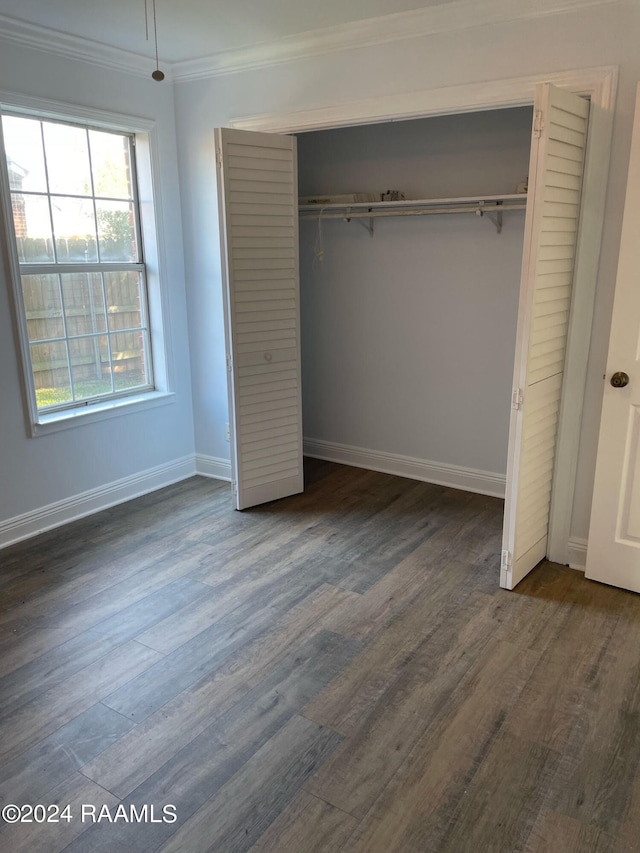 unfurnished bedroom with ornamental molding, a closet, and dark hardwood / wood-style flooring