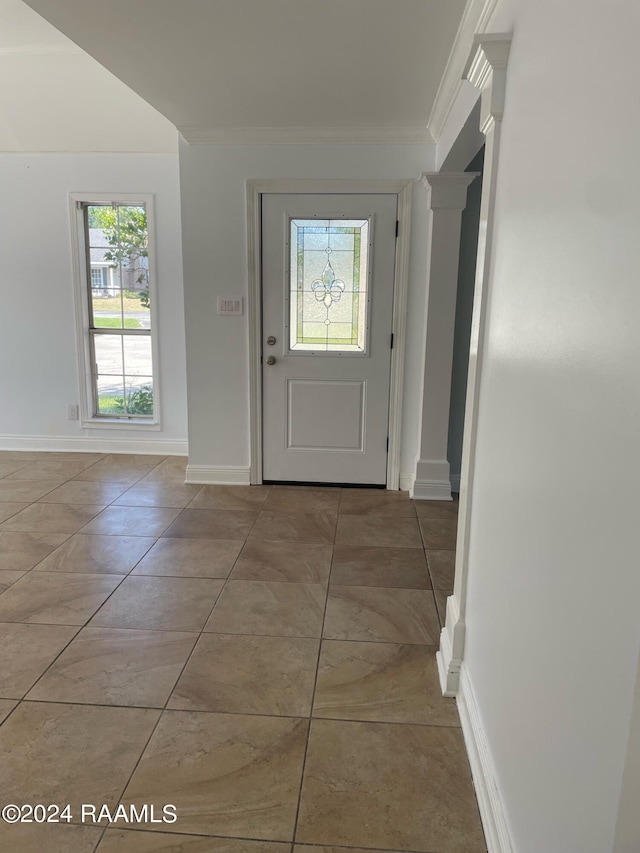 interior space with light tile patterned flooring, ornamental molding, and decorative columns