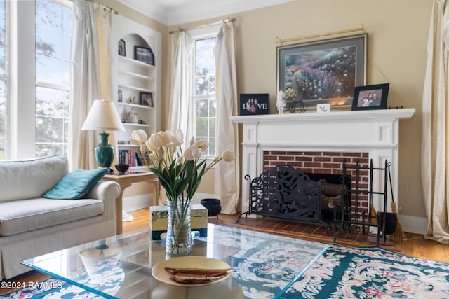 living area with wood finished floors, a brick fireplace, baseboards, and built in shelves