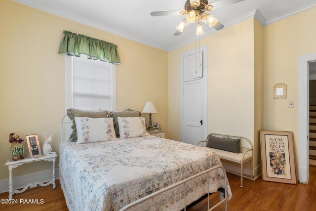 bedroom with a ceiling fan, crown molding, baseboards, and wood finished floors