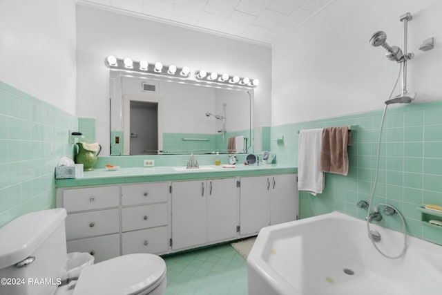 bathroom with toilet, vanity, a washtub, visible vents, and tile walls