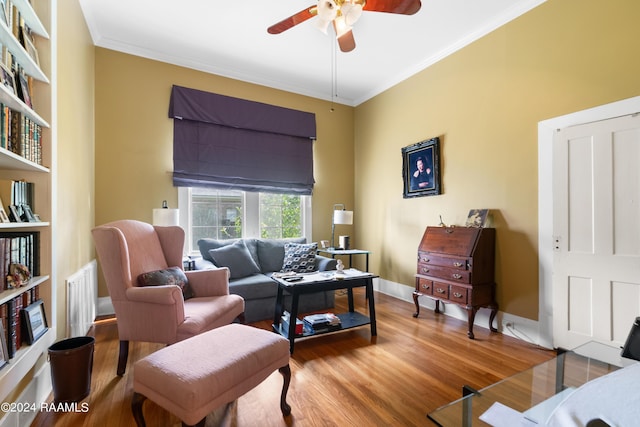 living area featuring wood finished floors, baseboards, visible vents, ceiling fan, and ornamental molding