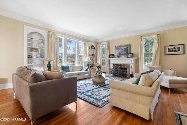 living area featuring crown molding, baseboards, a fireplace, built in shelves, and wood finished floors