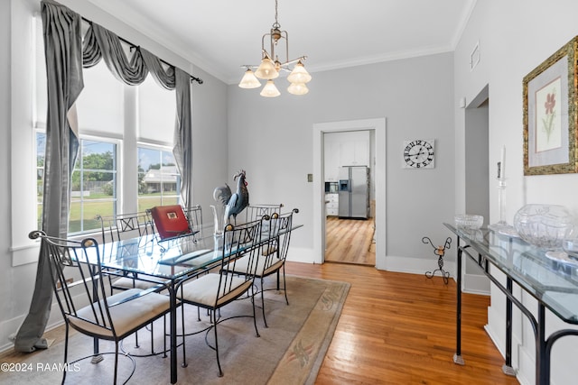 dining space with visible vents, baseboards, ornamental molding, wood finished floors, and an inviting chandelier