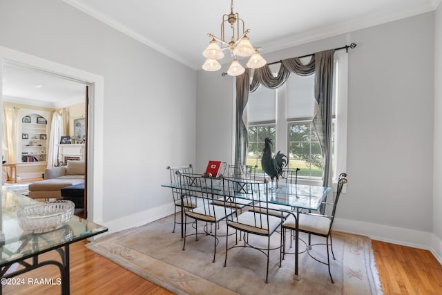 dining space featuring baseboards, wood finished floors, ornamental molding, and an inviting chandelier