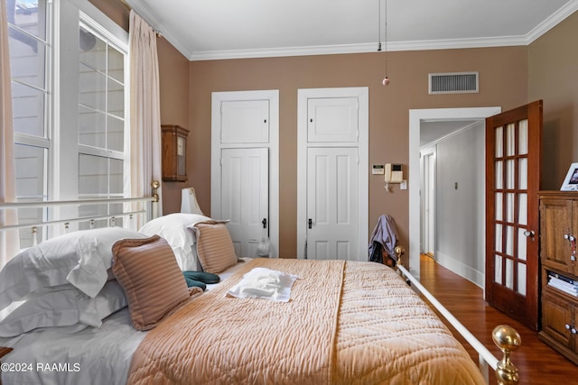 bedroom featuring visible vents, crown molding, and wood finished floors