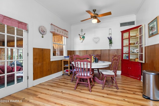 dining area with a wainscoted wall, visible vents, wood finished floors, and a ceiling fan