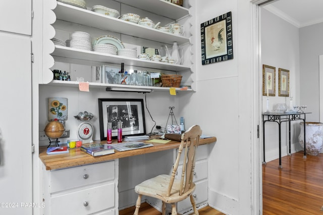 home office with built in desk, ornamental molding, and wood finished floors