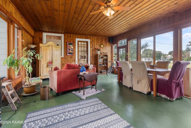 living room featuring wood walls, wood ceiling, concrete flooring, and a ceiling fan