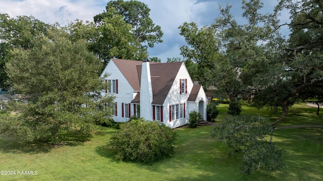 view of property exterior featuring a shingled roof, a yard, and a chimney
