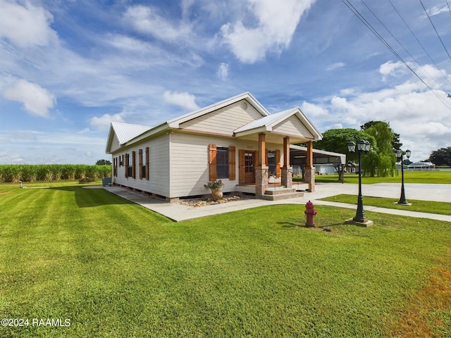 view of front facade with covered porch, metal roof, and a front lawn