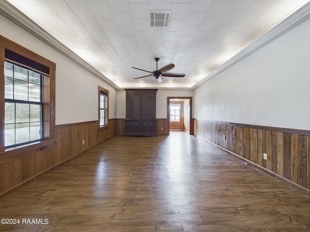 unfurnished room with a wainscoted wall, wood walls, visible vents, a ceiling fan, and dark wood finished floors