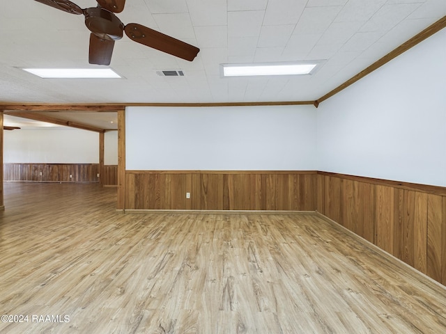 empty room with a wainscoted wall, wood finished floors, visible vents, and crown molding