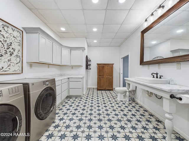 laundry area featuring light floors, washing machine and dryer, a sink, laundry area, and baseboards