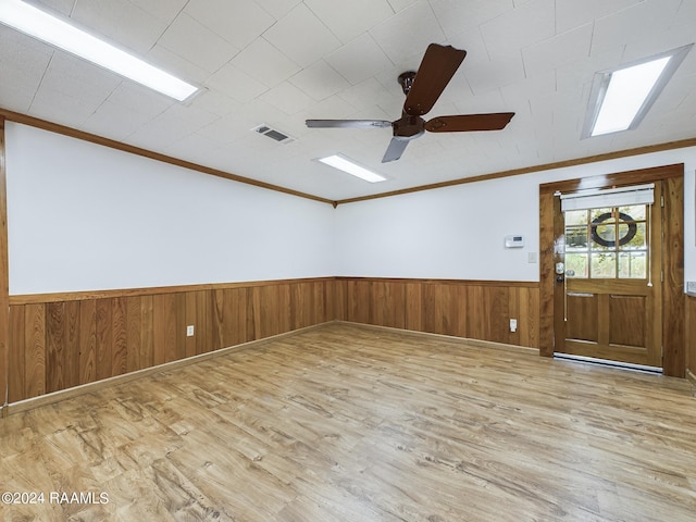 unfurnished room featuring ornamental molding, wainscoting, wood finished floors, and visible vents