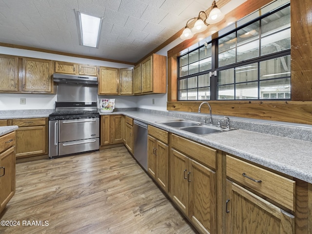 kitchen with appliances with stainless steel finishes, brown cabinetry, a sink, and under cabinet range hood