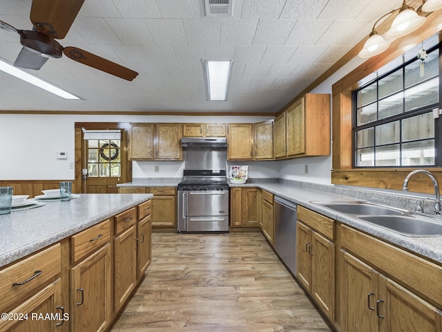 kitchen featuring brown cabinetry, stainless steel appliances, light wood-type flooring, under cabinet range hood, and a sink