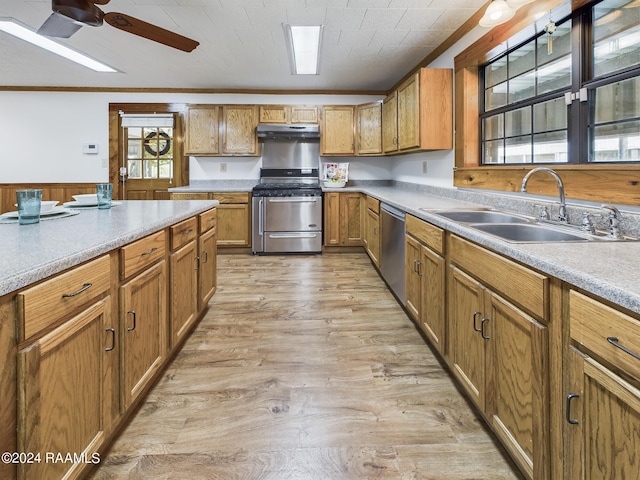 kitchen featuring crown molding, light wood finished floors, stainless steel appliances, a sink, and under cabinet range hood