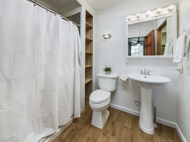 bathroom with crown molding, toilet, a sink, wood finished floors, and baseboards