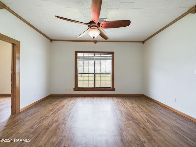 empty room with ceiling fan, ornamental molding, wood finished floors, and baseboards