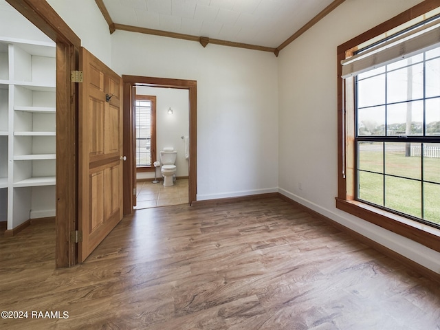 empty room with a healthy amount of sunlight, light wood finished floors, and ornamental molding