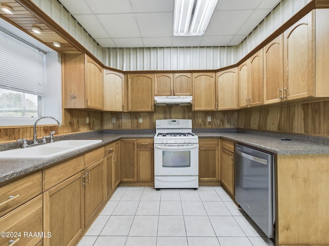 kitchen featuring a paneled ceiling, stainless steel dishwasher, a sink, under cabinet range hood, and white gas range oven