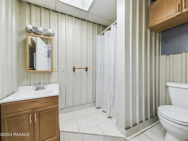 full bathroom with toilet, vanity, a paneled ceiling, and tile patterned floors