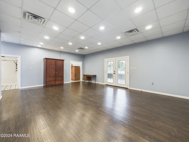 spare room with dark wood-style flooring, visible vents, a drop ceiling, and baseboards